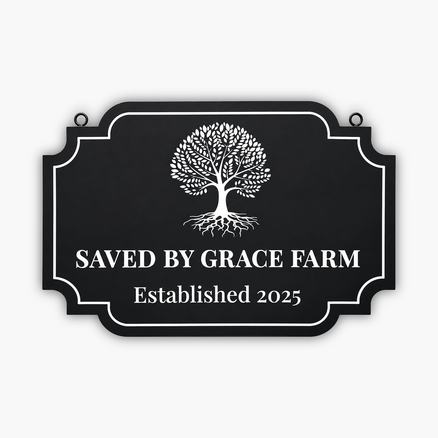 A black sign with a white tree graphic and the text SAVED BY GRACE FARM Established 2025 written in large, bold letters. The sign has a decorative border and is mounted on a wooden wall.