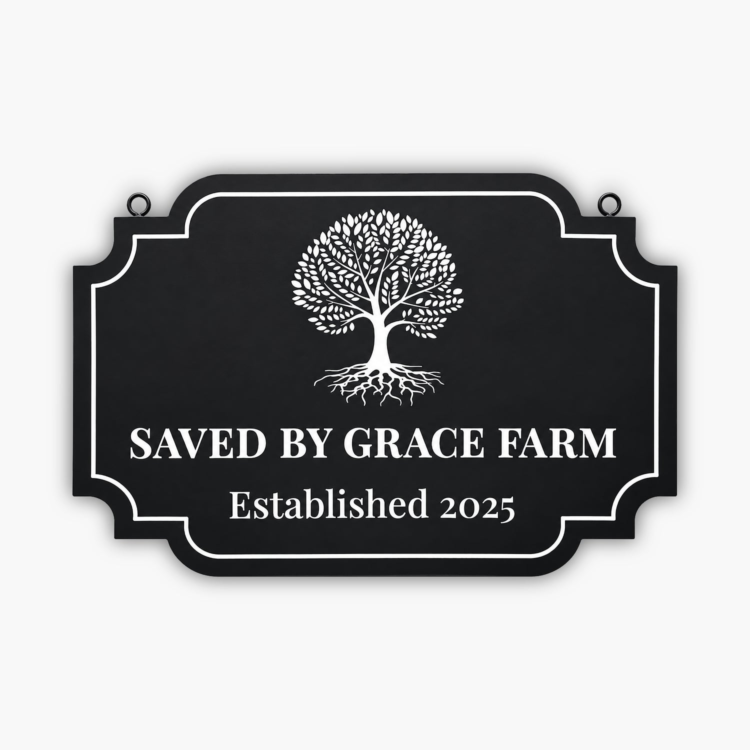 A black sign with a white tree graphic and the text SAVED BY GRACE FARM Established 2025 written in large, bold letters. The sign has a decorative border and is mounted on a wooden wall.