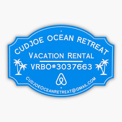 Custom PVC sign for Cudjoe Ocean Retreat, featuring a blue background with white engraved text and graphics. Includes vacation rental details, VRBO#3037663, email address, and palm tree illustrations, emphasizing weatherproof durability and elegance.