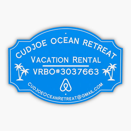Custom PVC sign for Cudjoe Ocean Retreat, featuring a blue background with white engraved text and graphics. Includes vacation rental details, VRBO#3037663, email address, and palm tree illustrations, emphasizing weatherproof durability and elegance.