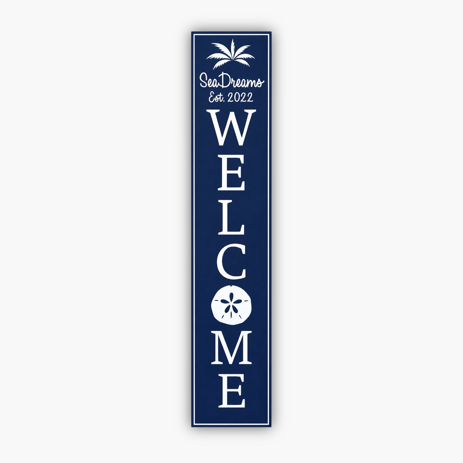 Tall blue vertical welcome sign with white text reading Sea Dream and Est. 2022 at the top, with a palm tree graphic. Large vertical WELCOME text follows, featuring a sand dollar graphic within the O. The background is a beige siding wall.
