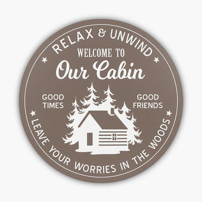 The Custom Carved Round PVC Cabin Sign displays a serene cabin and tree silhouette with the text: Relax & Unwind. Welcome to Our Cabin. Good Times. Good Friends. Leave Your Worries in the Woods. Its designed with a brown background and white graphics, ideal for personalizing your retreat space.