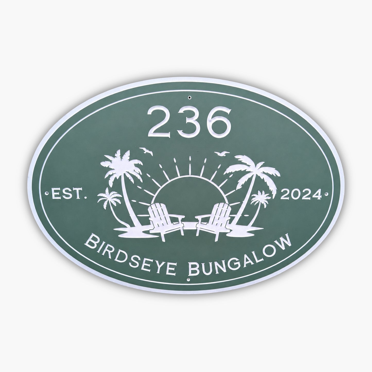 The Personalized Oval Custom Beach House Sign is green with white text, displaying 236 Birdseye Bungalow and Est. 2024. It features a sun setting behind two palm trees and lounge chairs, surrounded by birds.