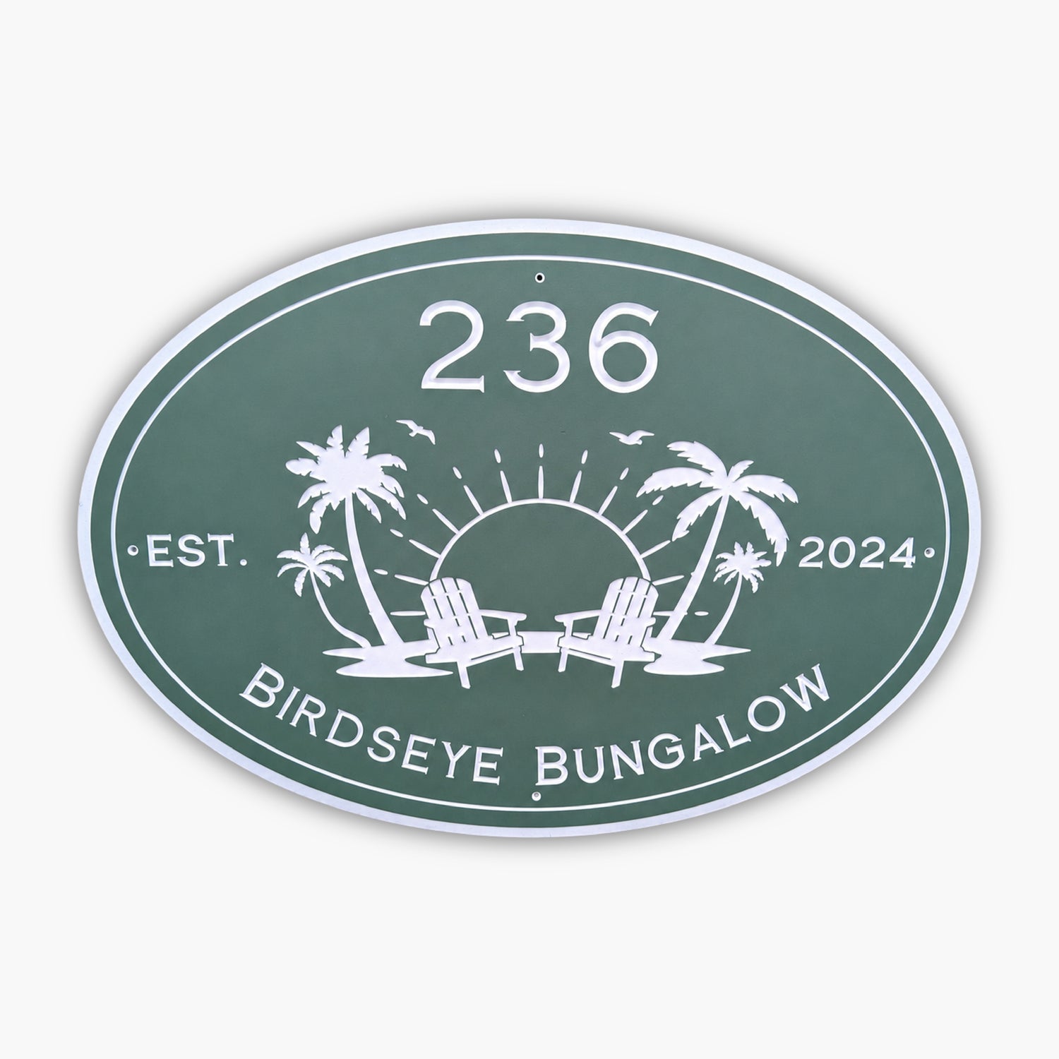 The Personalized Oval Custom Beach House Sign is green with white text, displaying 236 Birdseye Bungalow and Est. 2024. It features a sun setting behind two palm trees and lounge chairs, surrounded by birds.