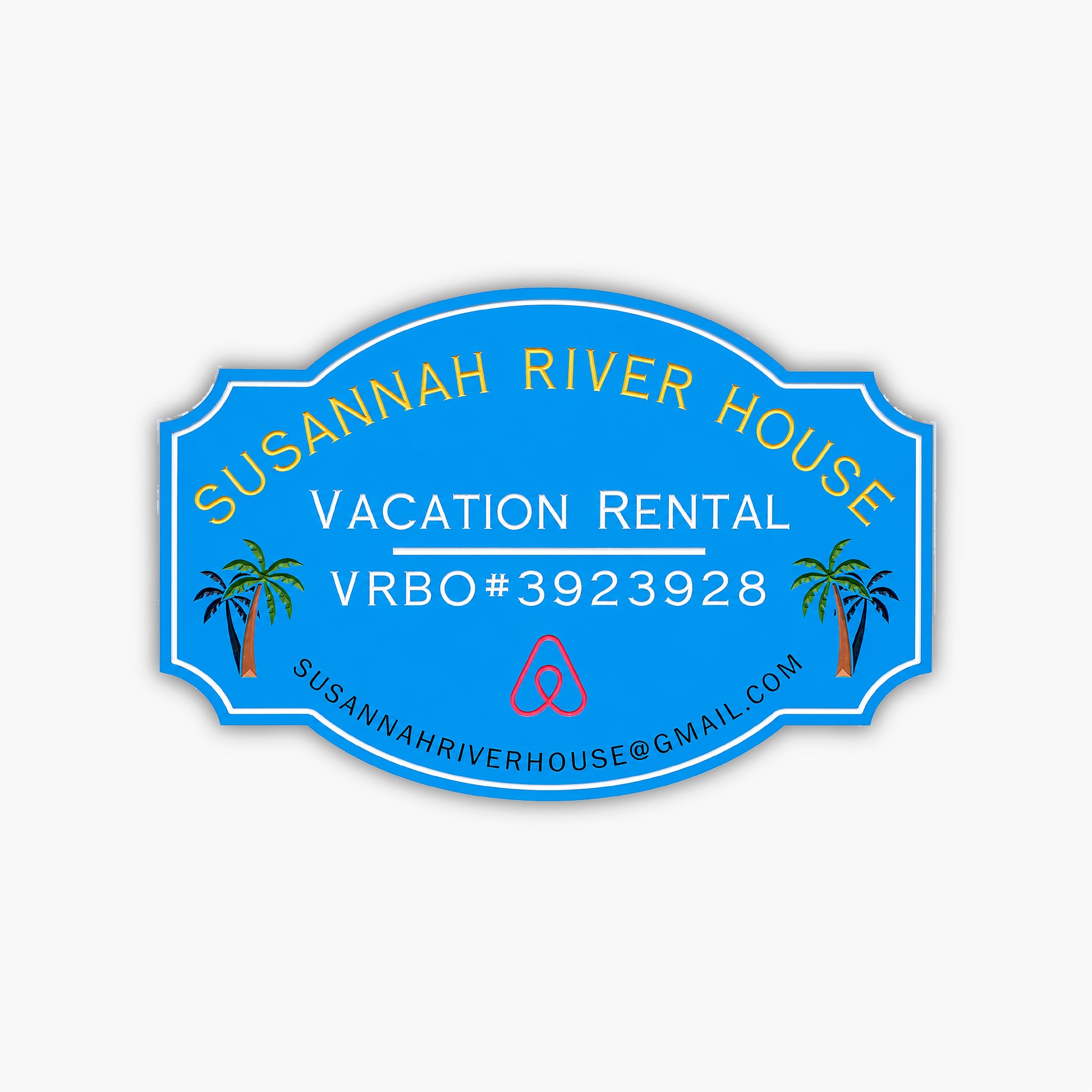 A custom home rental sign for Susannah River House features vibrant yellow and white text on a blue oval background with Vacation Rental VRBO#3923928, an Airbnb logo, palm tree illustrations, and the email address susannahriverhouse@gmail.com.