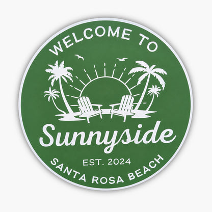A personalized Beach House sign in green with white text and graphics reads Welcome to Sunnyside, Est. 2024, Santa Rosa Beach, featuring two chairs, palm trees, a sun with rays, and birds.