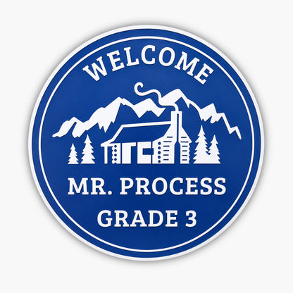 Sign in blue with white text and graphics: Welcome at the top, featuring an illustration of a cabin amidst trees and mountains, resembling charming coastal decor. The bottom reads Mr. Process Grade 3.