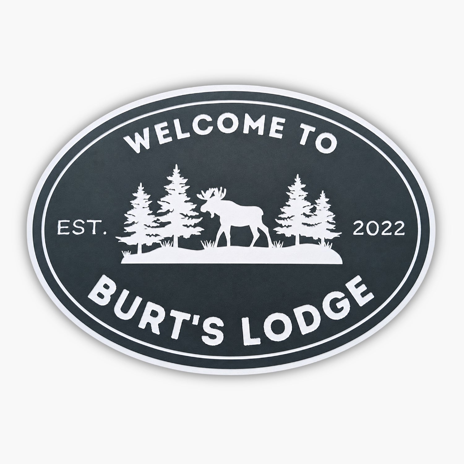 The Personalized Oval Custom Beach House Sign features Welcome to Burts Lodge, showcasing a moose and pine trees silhouette. Its dark background with white lettering reads Est. 2022, echoing the elegance of classic coastal decor.
