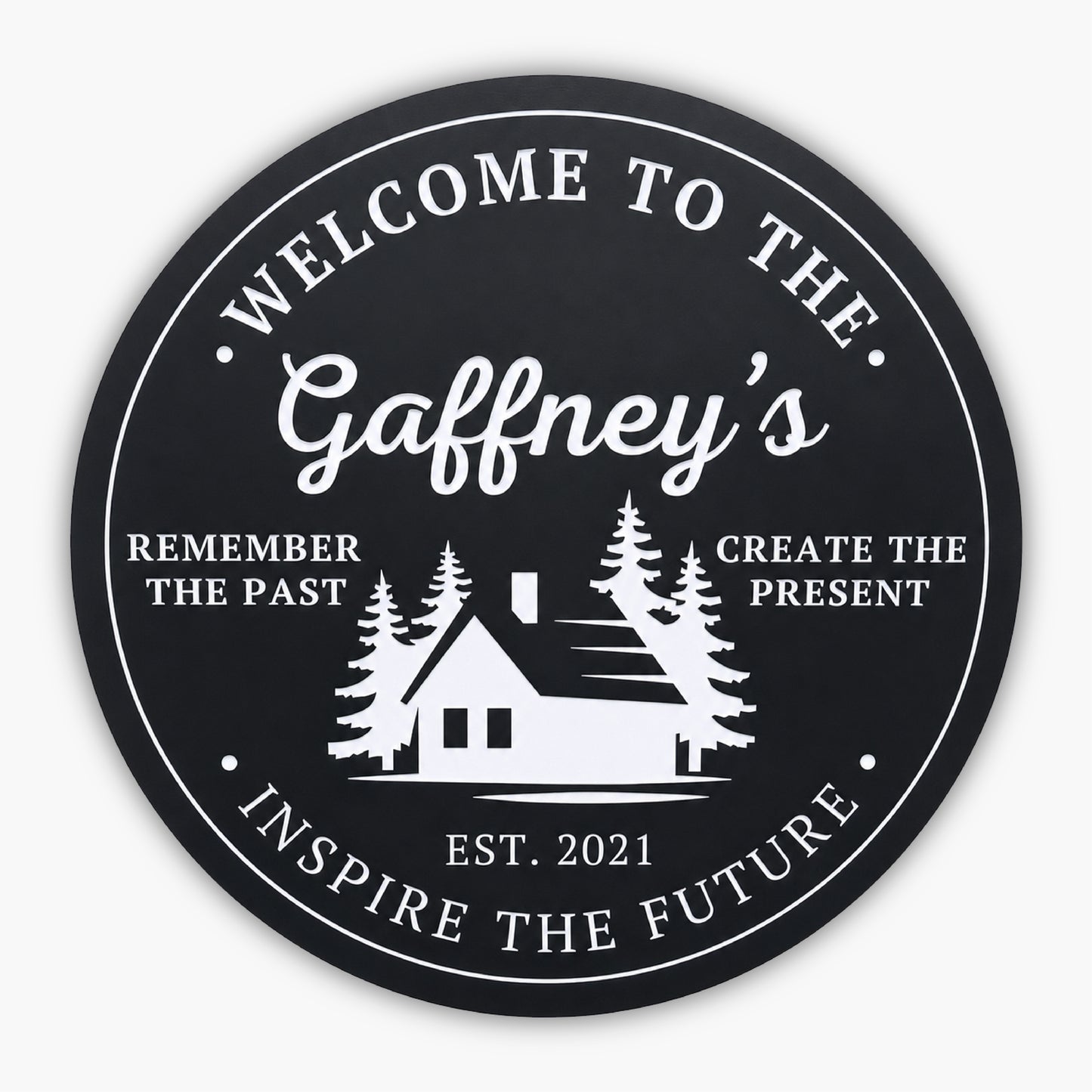 The Personalized Round Cabin Sign features a black circular background with white text: Welcome to the Gaffneys at the top. A custom cabin silhouette and trees grace the center, flanked by Remember the Past, Create the Present. Below is Est. 2021, with Inspire the Future at the bottom.