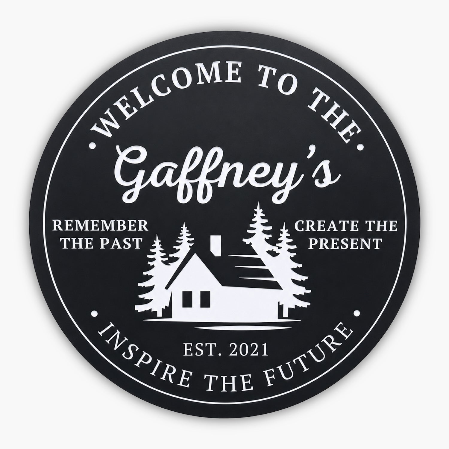 The Personalized Round Cabin Sign features a black circular background with white text: Welcome to the Gaffneys at the top. A custom cabin silhouette and trees grace the center, flanked by Remember the Past, Create the Present. Below is Est. 2021, with Inspire the Future at the bottom.
