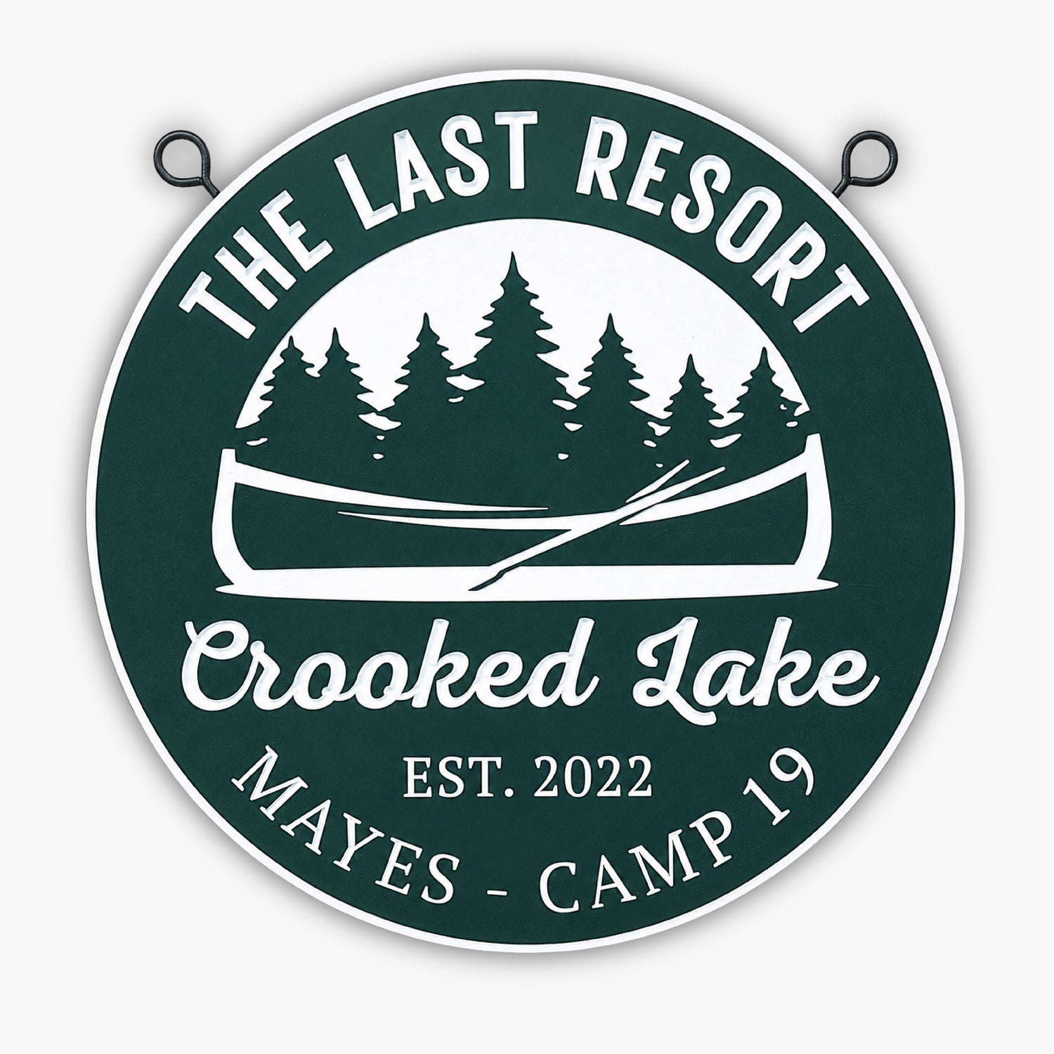 A round green and white sign with trees, a canoe, and paddles. Text reads: The Last Resort, Crooked Lake, Est. 2022, Mayes - Camp 19.